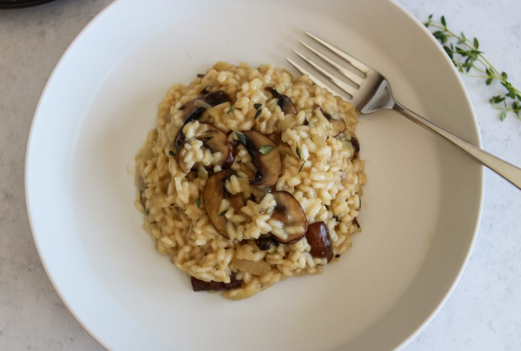 Top view of risotto in a white bowl with a silver spoon. 