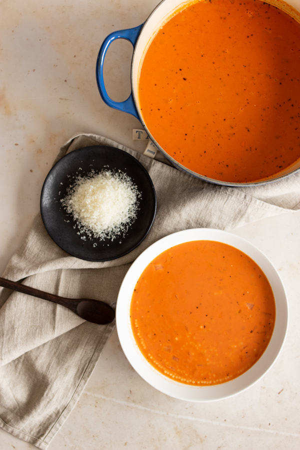 Top view of bowl of soup with dutch oven full of tomato soup. 
