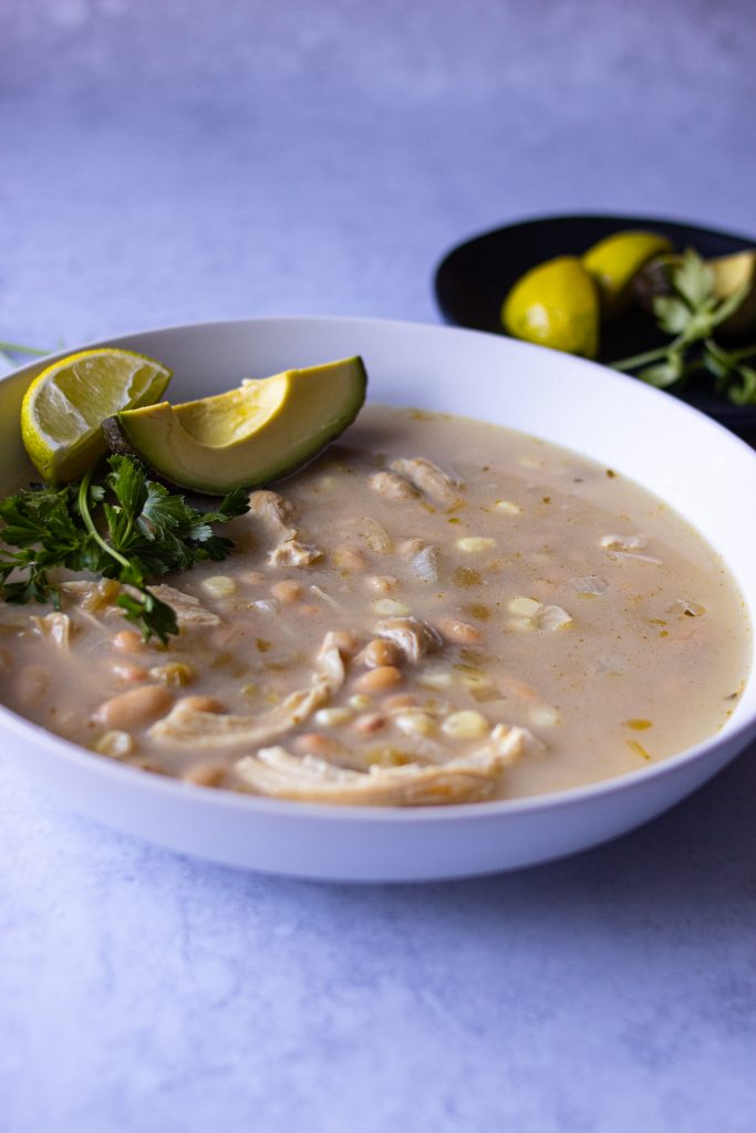 White chicken chili with avocado slice and lime wedge on top. 