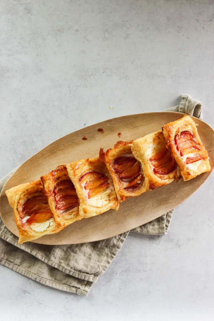 upside down peach puff pastries on a wooden serving platter. 