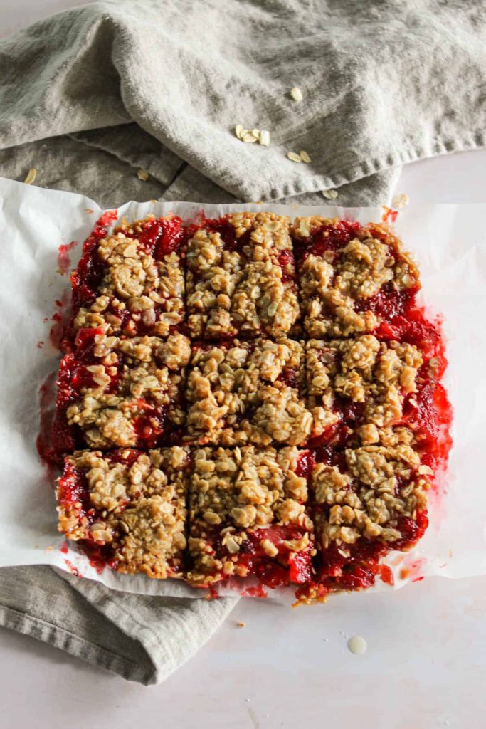 Strawberry steel cut oatmeal bars on a piece of parchment paper in a square. 