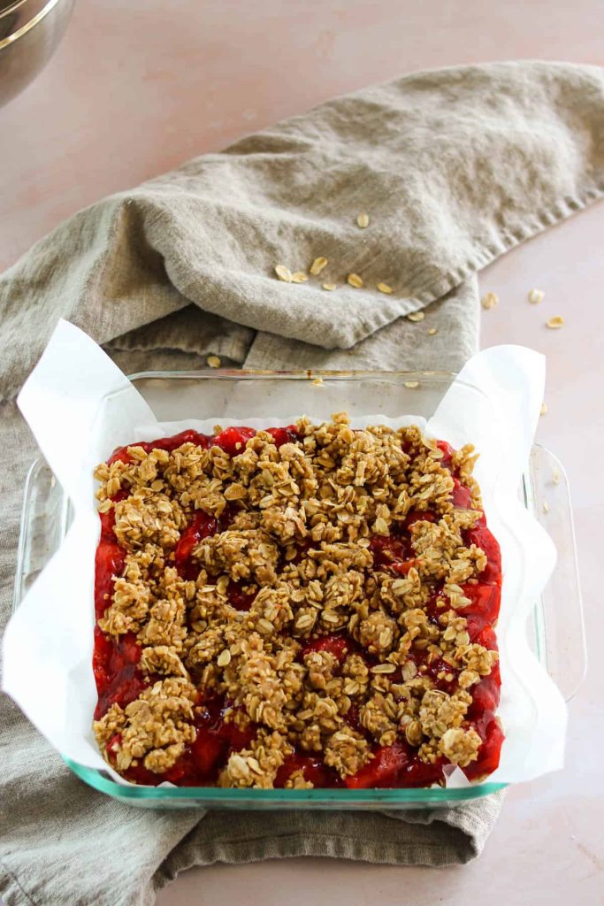 More oatmeal mixture on top of the strawberry mixture in a baking dish. 