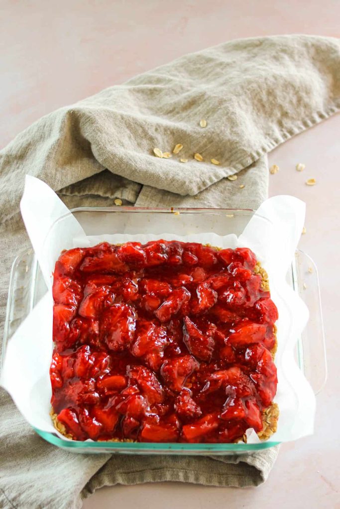 Strawberry jam layered on top of oats in a baking dish. 