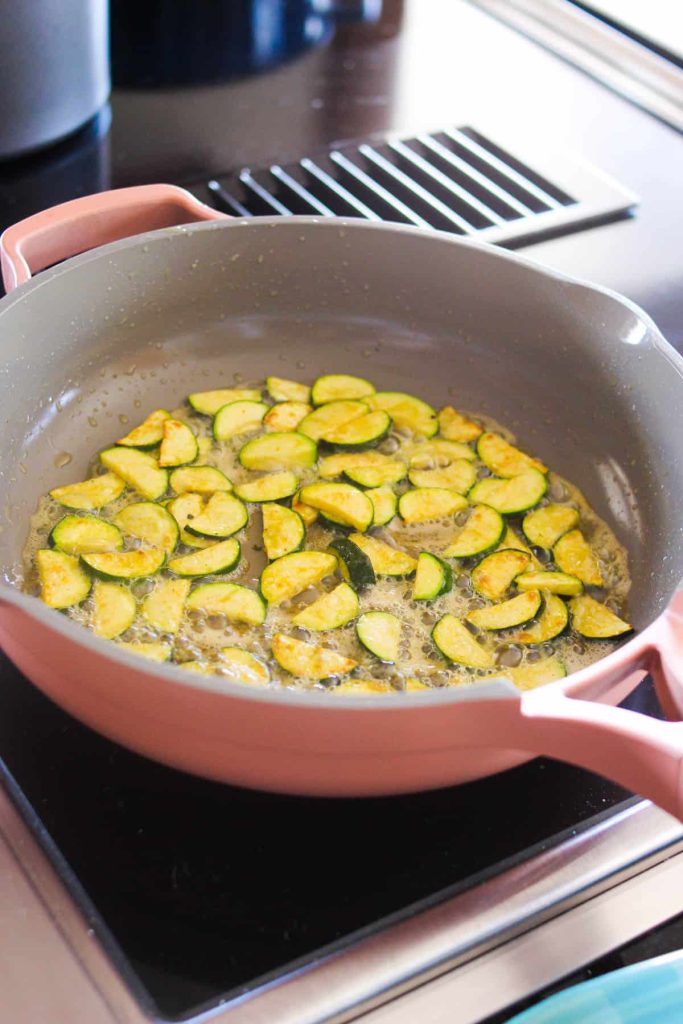 Zucchini being cooked in a sauté pan. 