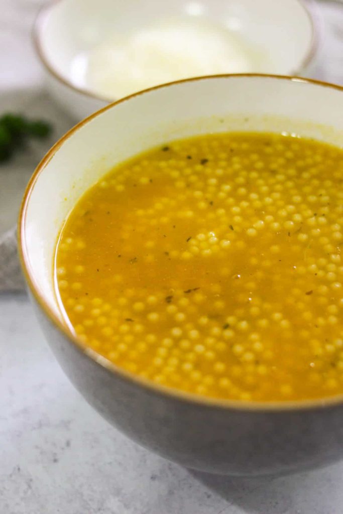 Close up shot of chicken soup with acini di pepe in a bowl. 