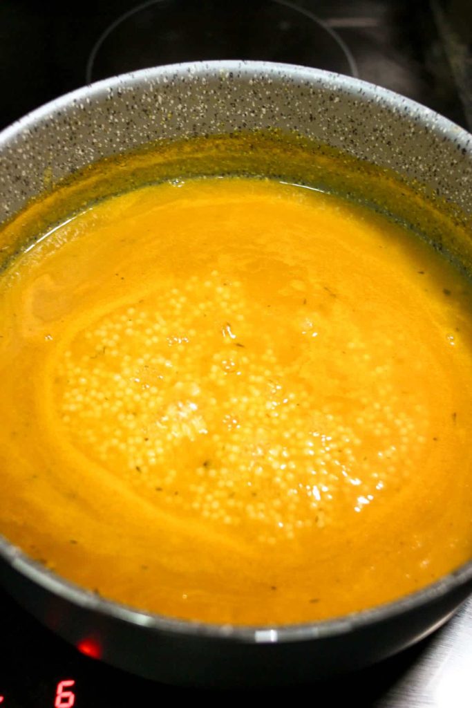 Chicken pastina soup simmering in a pot on the stove. 