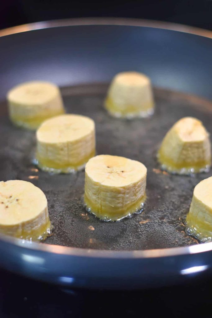 Plantain chunks frying in oil on the stove. 