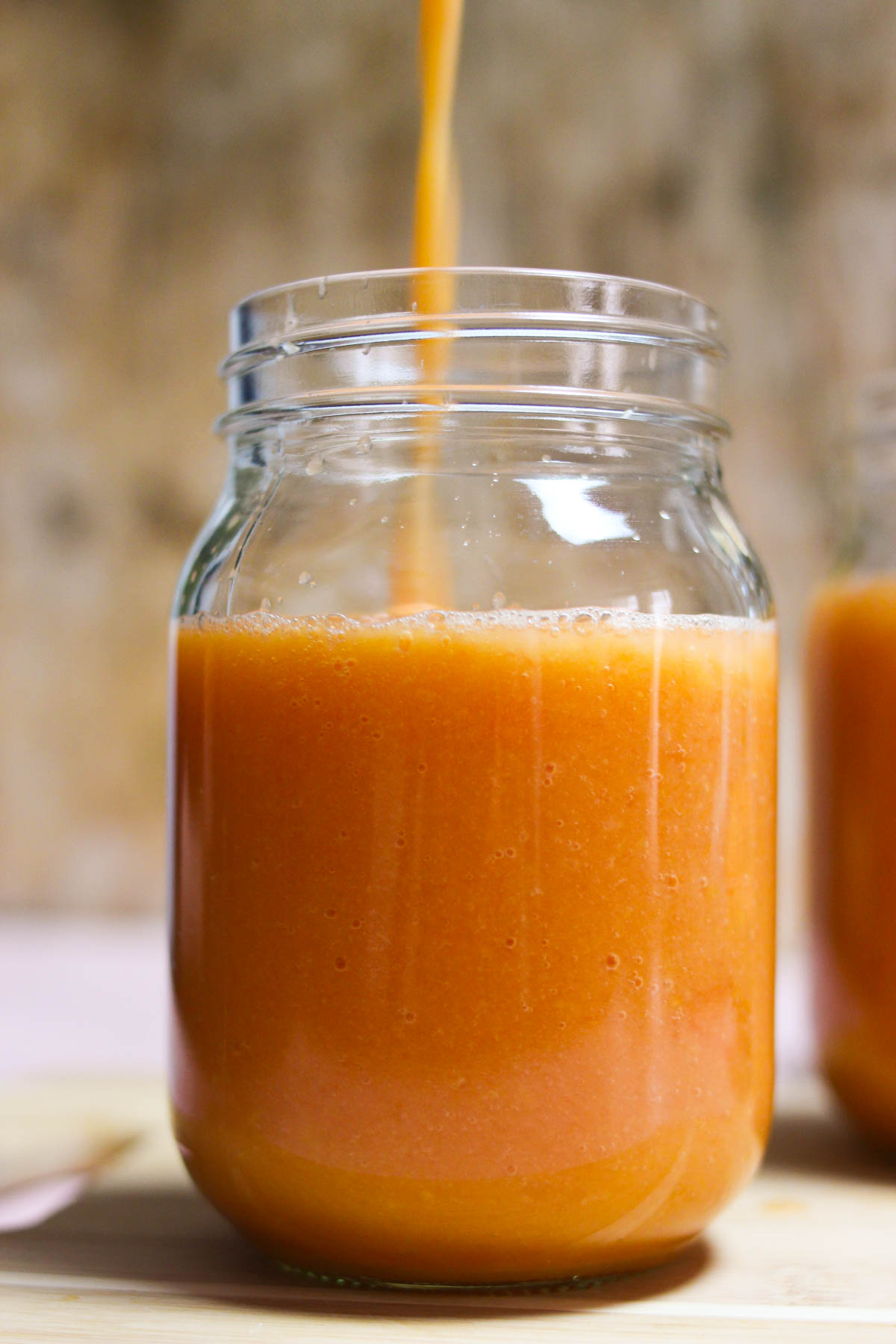 Papaya mango smoothie being poured into a glass jar. 