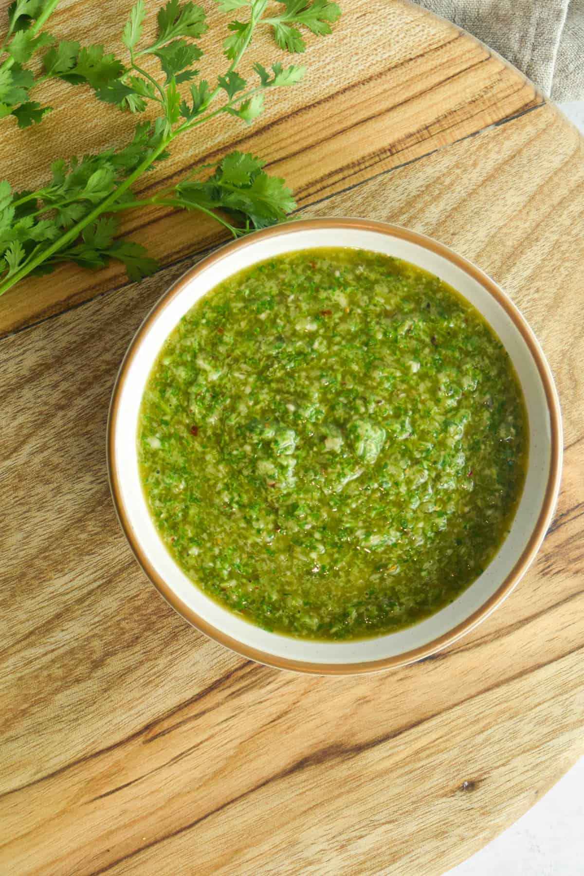 Cilantro chimichurri in a small bowl on a wooden background.