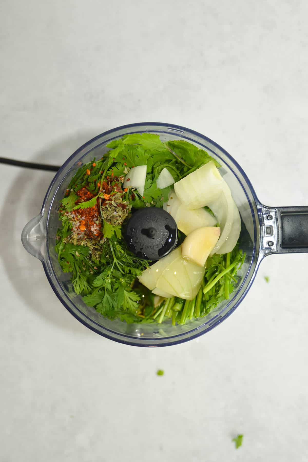 Ingredients for cilantro chimichurri in the food processor before being blended.