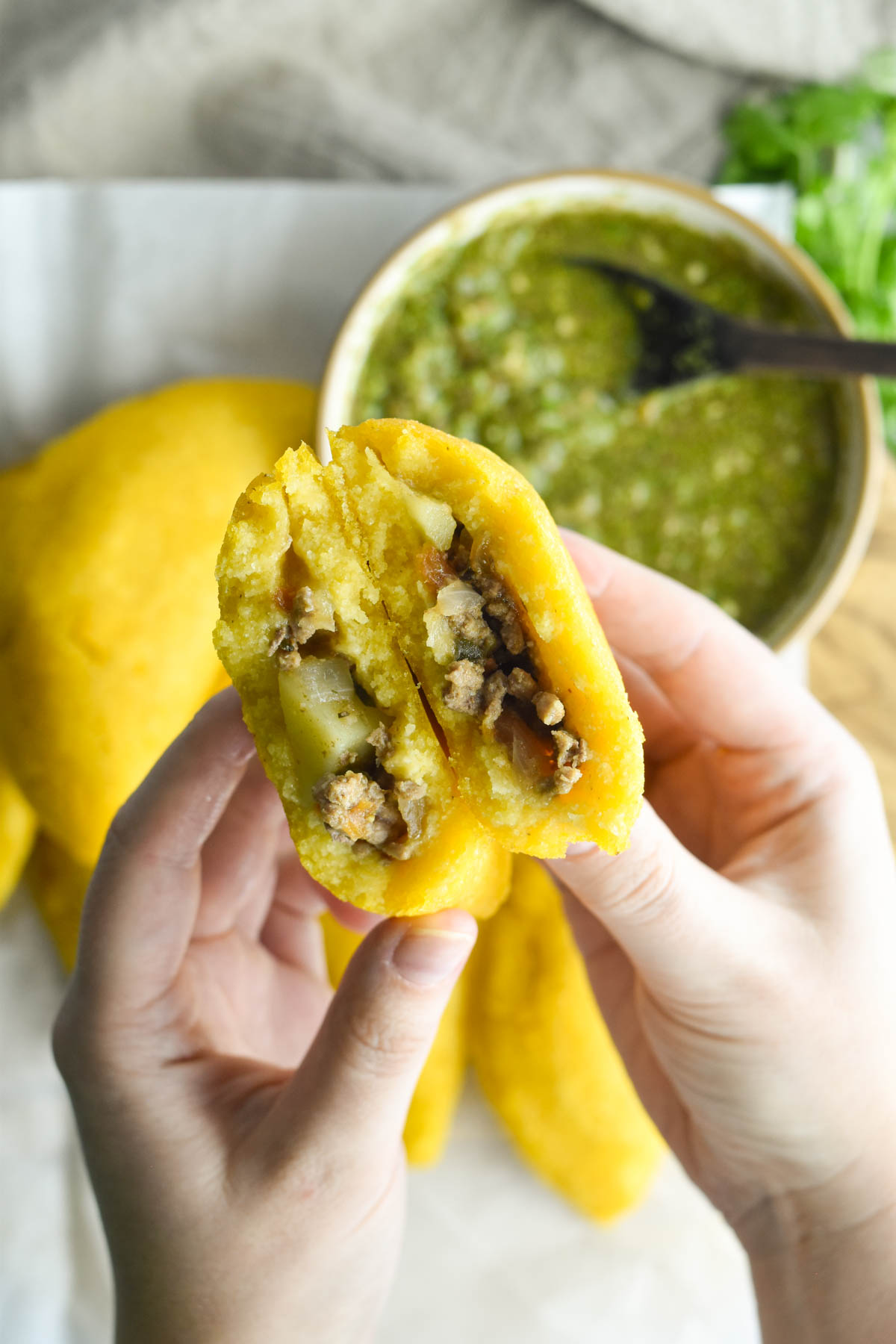 Hand holding an two halves of an empanada to show the inside. 