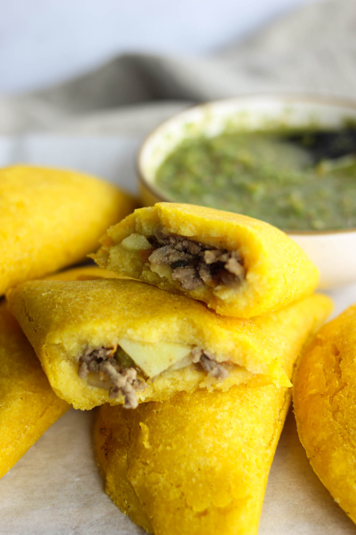 Colombian empanadas stacked on top of each other with one broken in half to show the inside. 