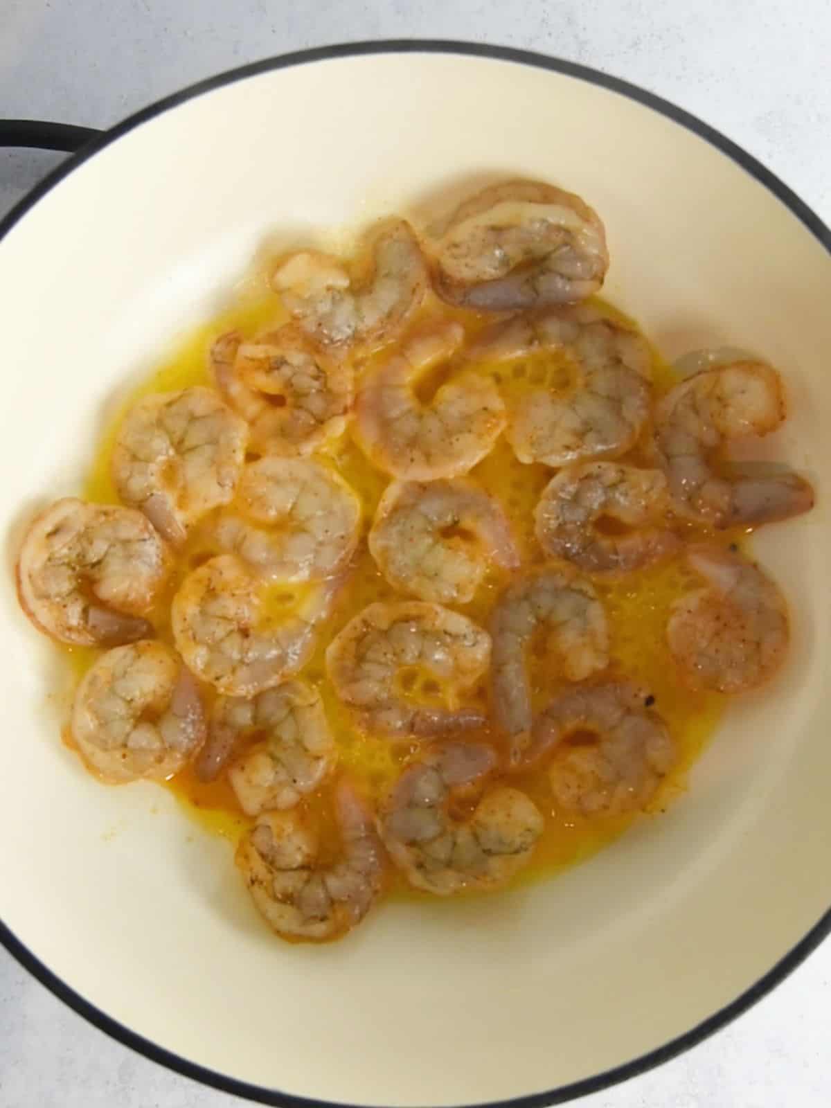 Shrimp being cooked in a skillet in butter and oil.