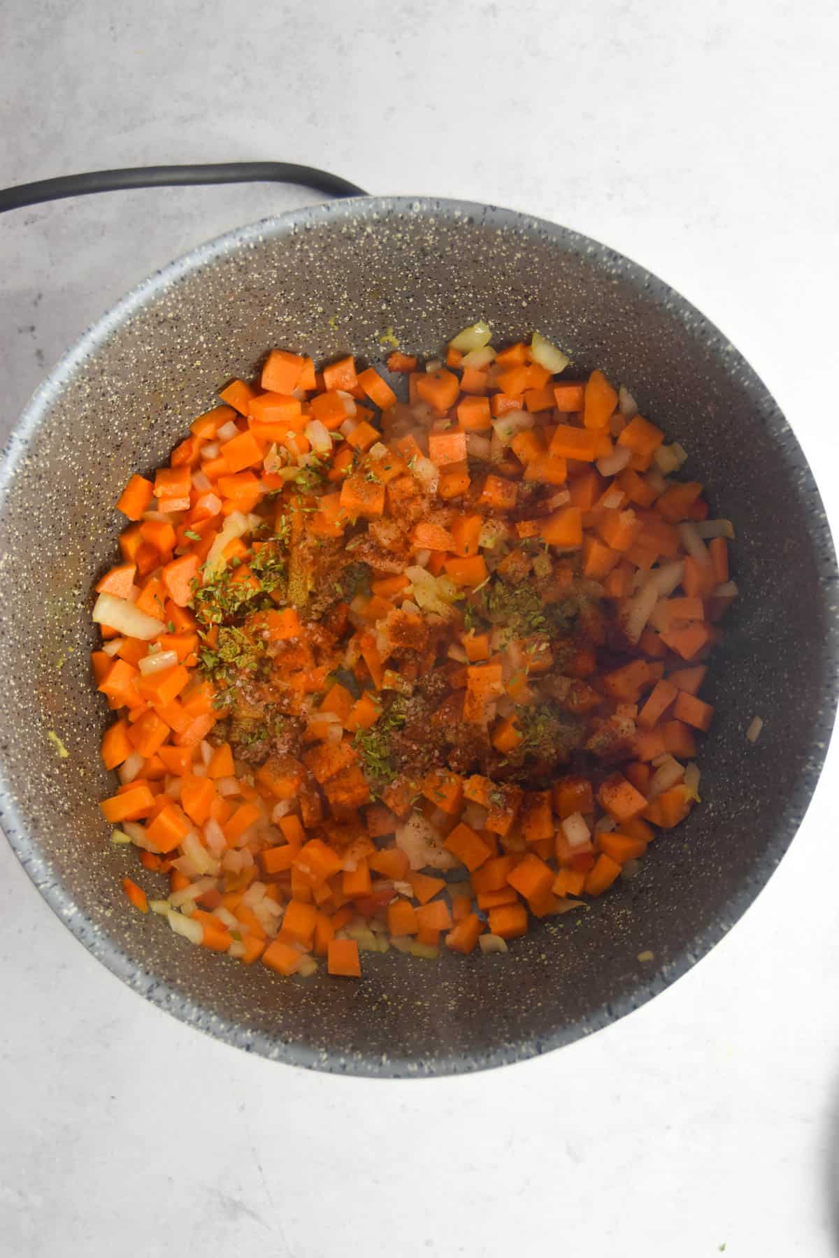 Spices added to the vegetables in a stock pot.