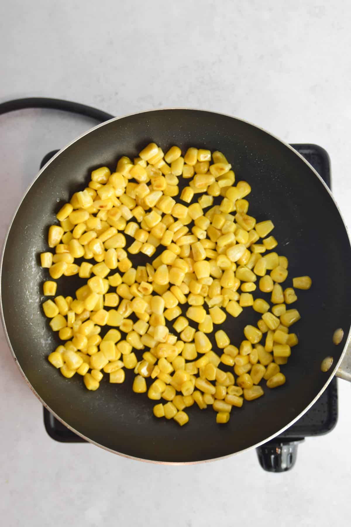 Frozen corn being browned in a skillet.