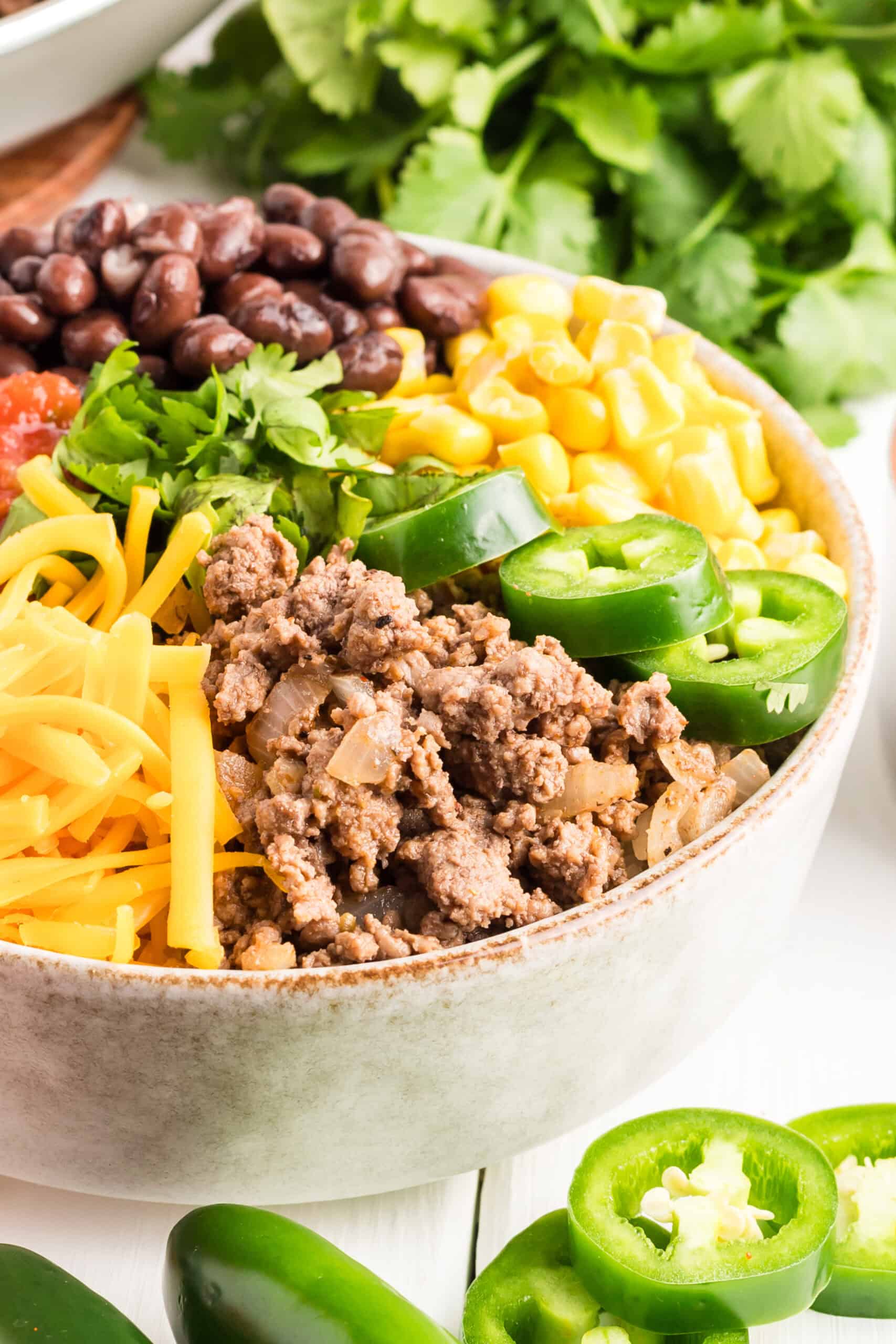 Ground beef bowl in a gray speckled bowl with vegetables and beans on top.