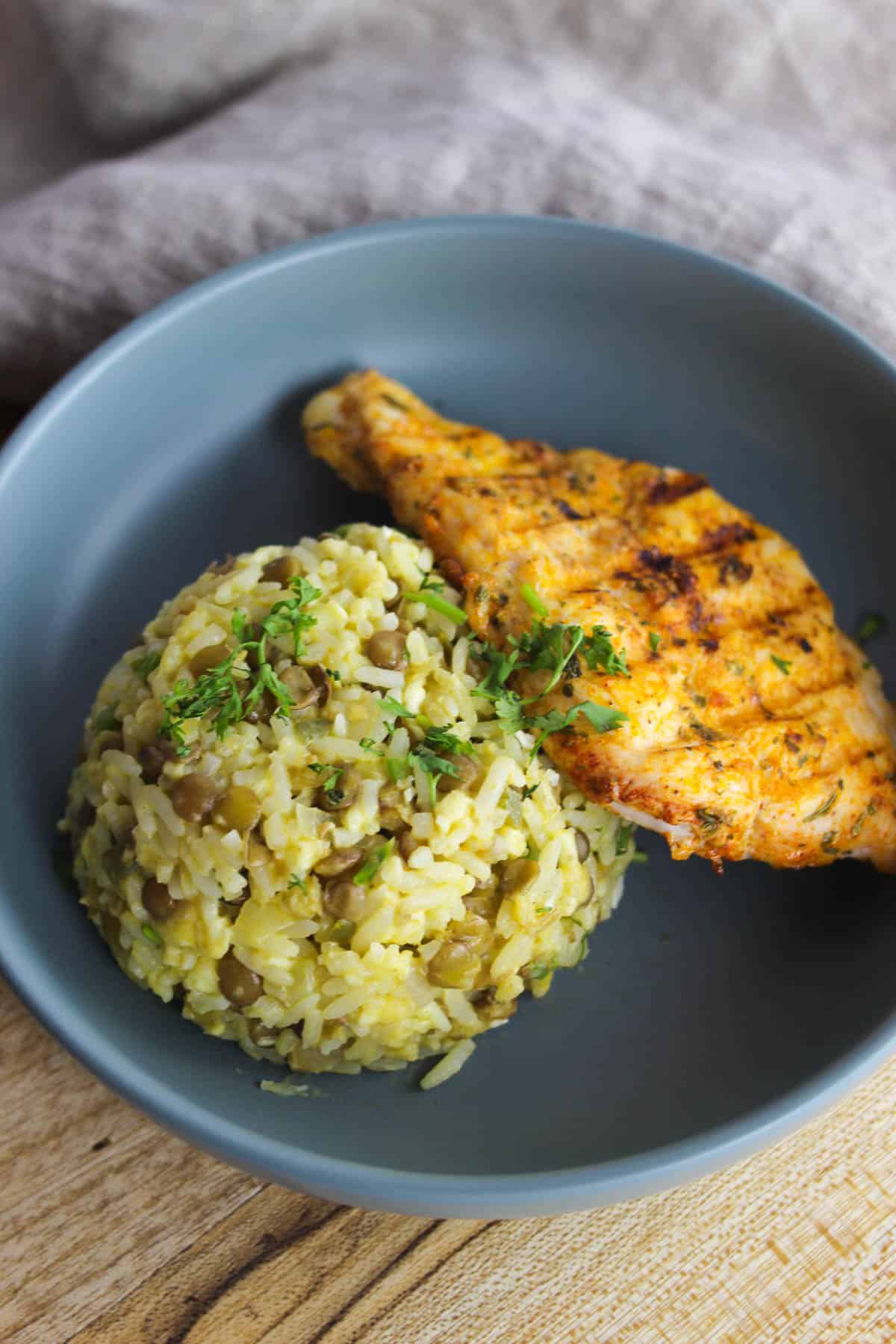 Dish of moro de lentejas with cast iron chicken breast garnished with cilantro.