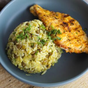 Mound of rice and lentils with chicken breast in a bowl.