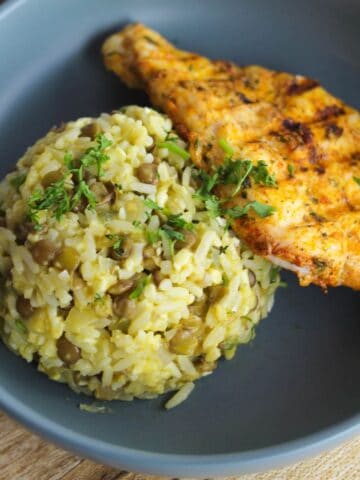 Mound of rice and lentils with chicken breast in a bowl.