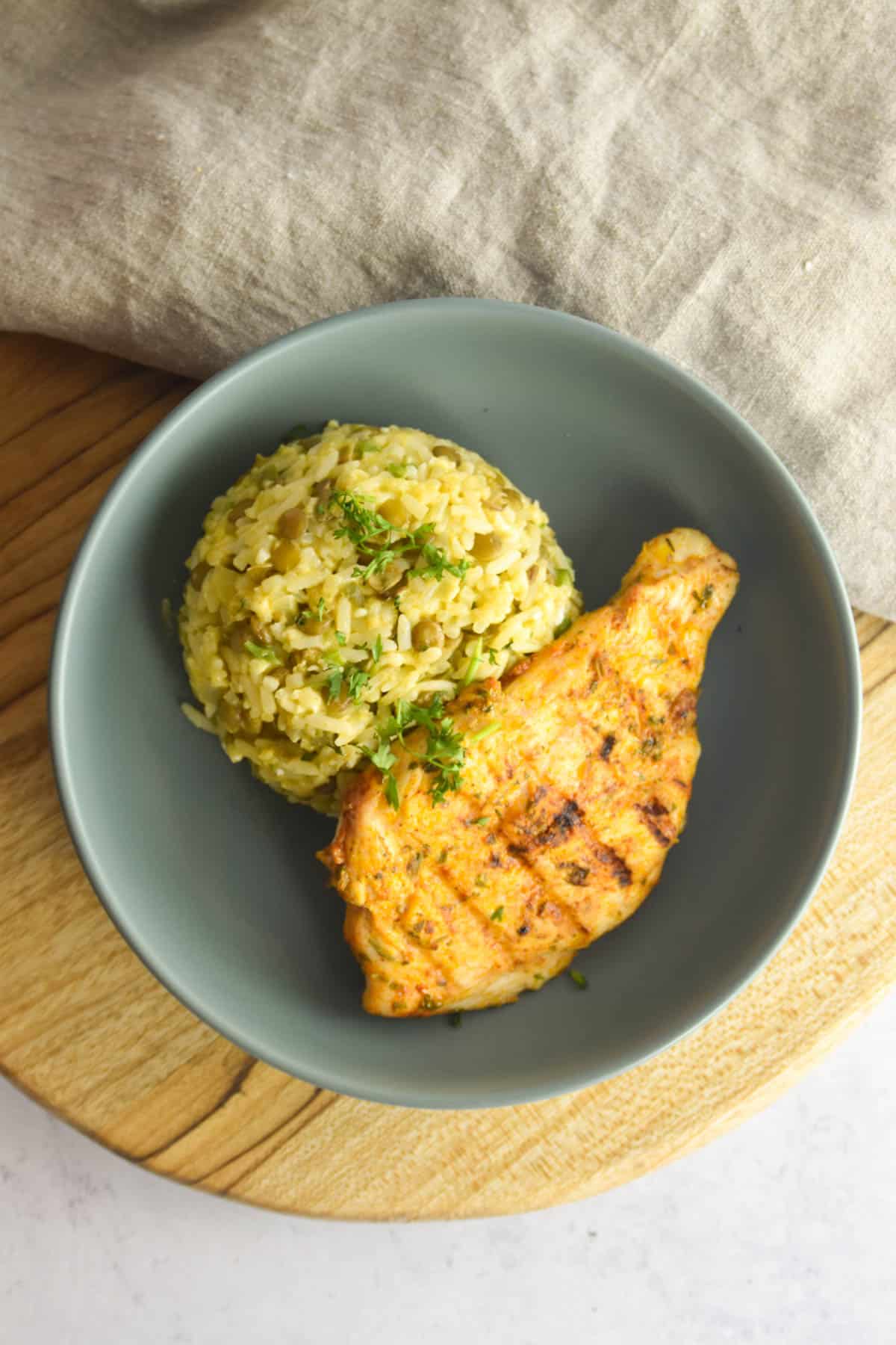 Grey plate with a mound of moro de lentejas and a chicken breast.