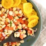 Overhead shot of cevichochos in a bowl with chifles and a wooden spoon.