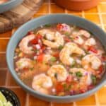 Ecuadorian shrimp ceviche served in a blue bowl on a red tile background.