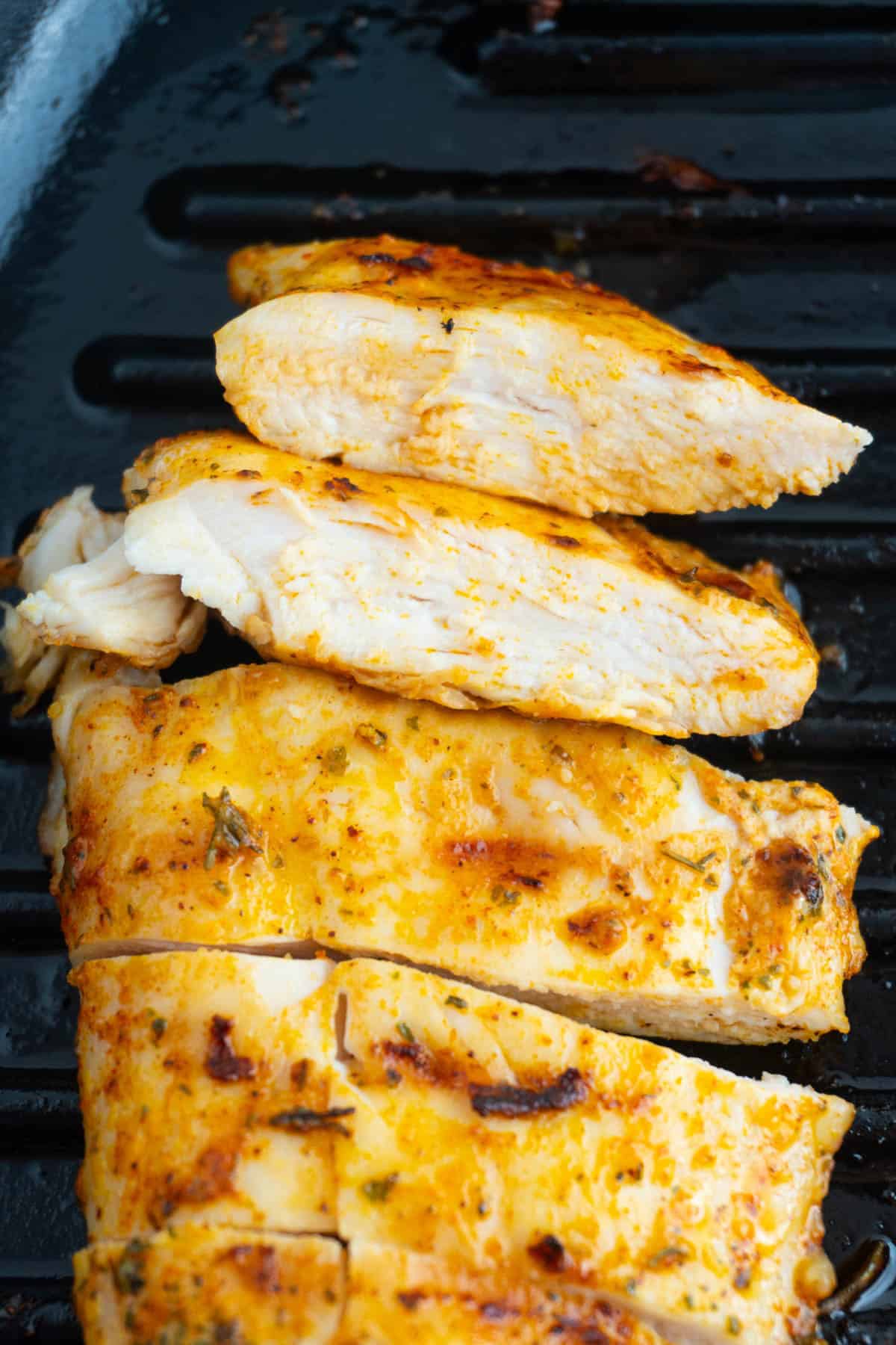 Close up of chicken breast slices in a cast iron pan.