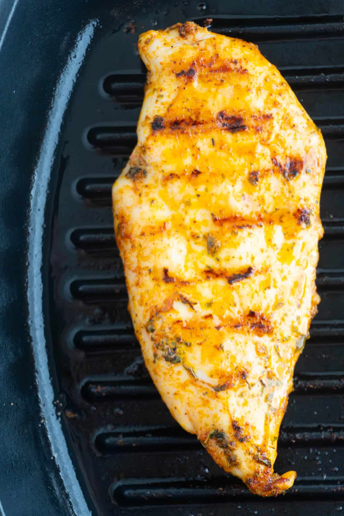 Overhead shot of a cast iron chicken breast with grill lines.