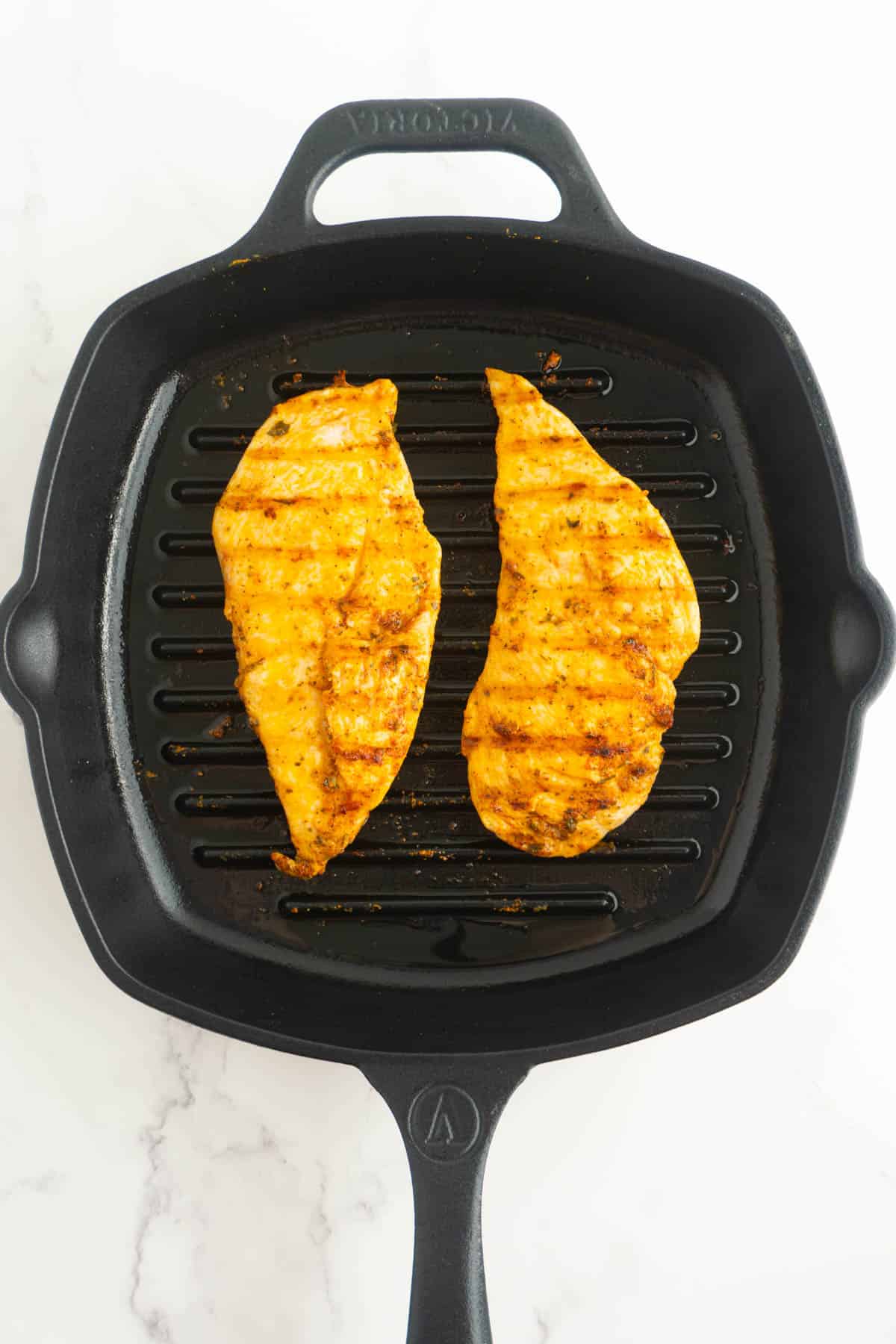 Chicken breasts in the cast iron after being flipped.