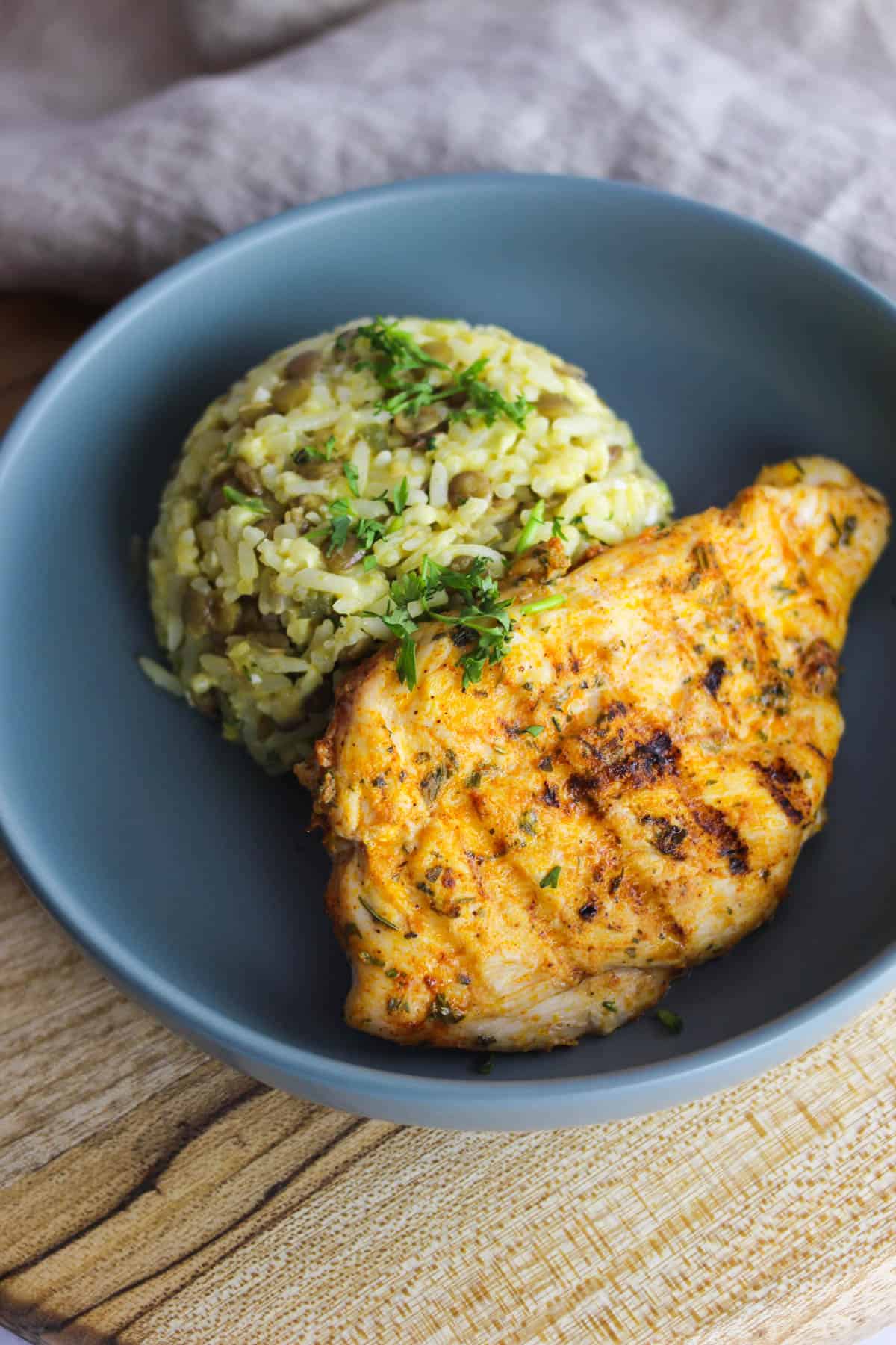 Cast iron chicken breast served with moro de lentejas in a shallow bowl.