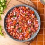 Tomato onion salad in a bowl with cilantro on top.