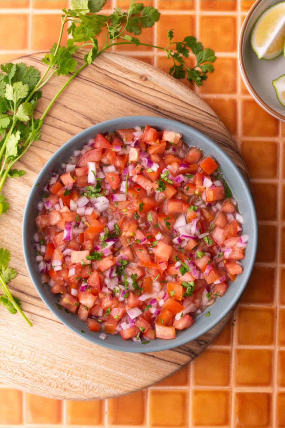 Tomato and onion curdito served in a shallow blue bowl on a wooden board.