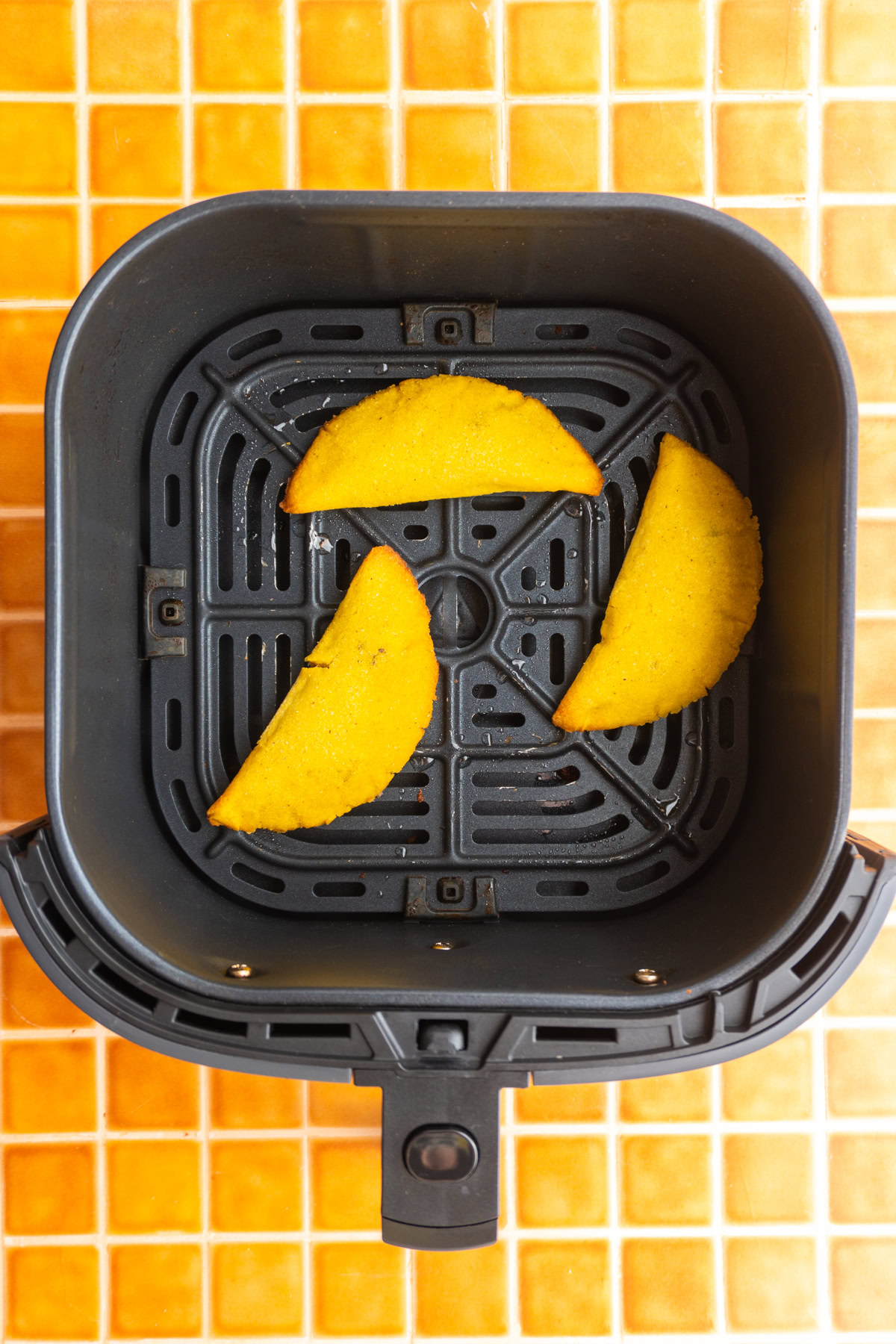 Colombian empanadas in an air fryer basket.