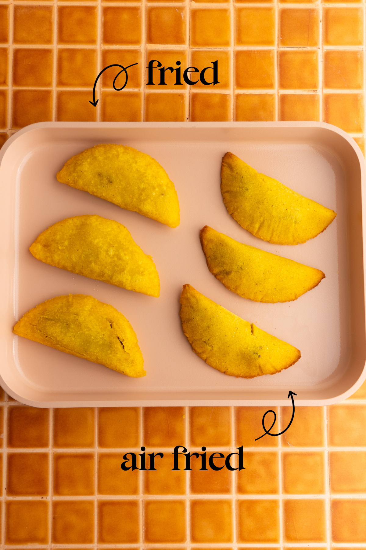 Colombian empanadas on a sheet plan with the ones on the left labeled as "fried" and the ones on the right labeled as "air fried".