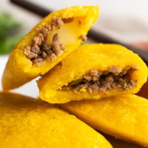 Close up of one empanada cut in half leaning on other empanadas.