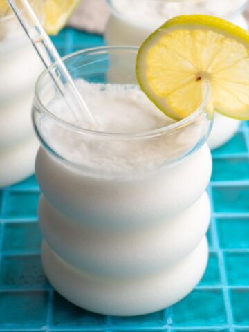 Limonada de coco served with a glass straw and a lime wheel.