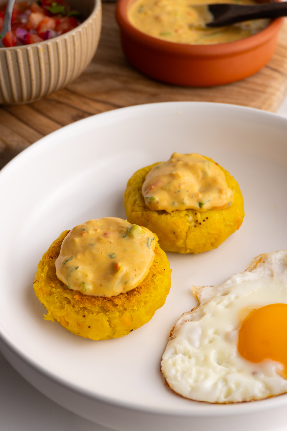 Peanut sauce on top of two tortillas de verde in a plate.