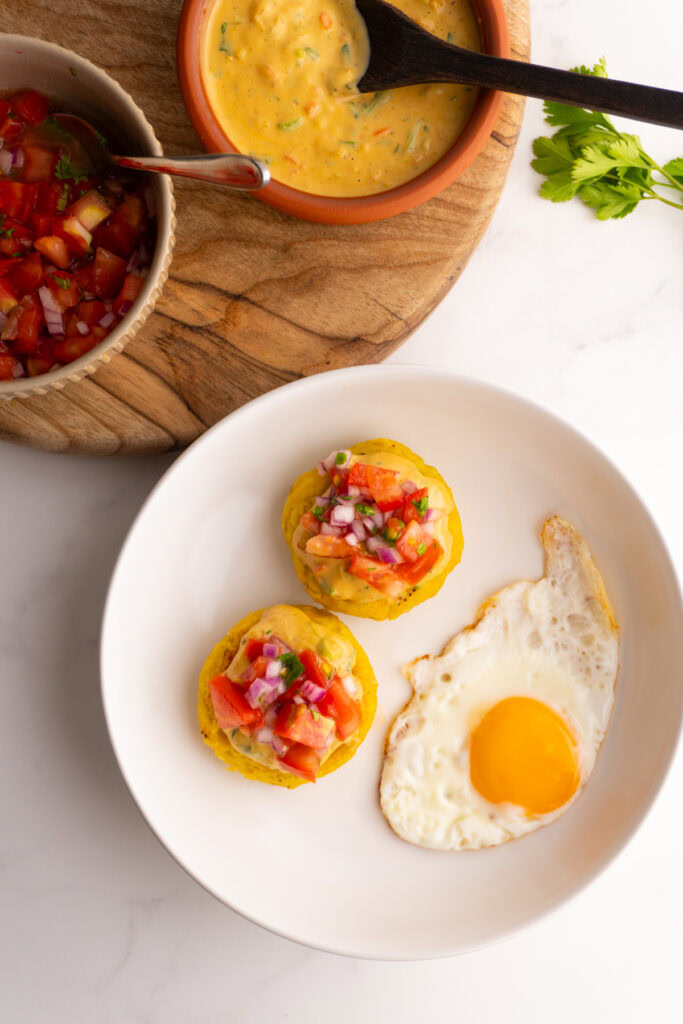 White bowl served with tortillas de verde and an egg with a bowl of peanut sauce on the side.