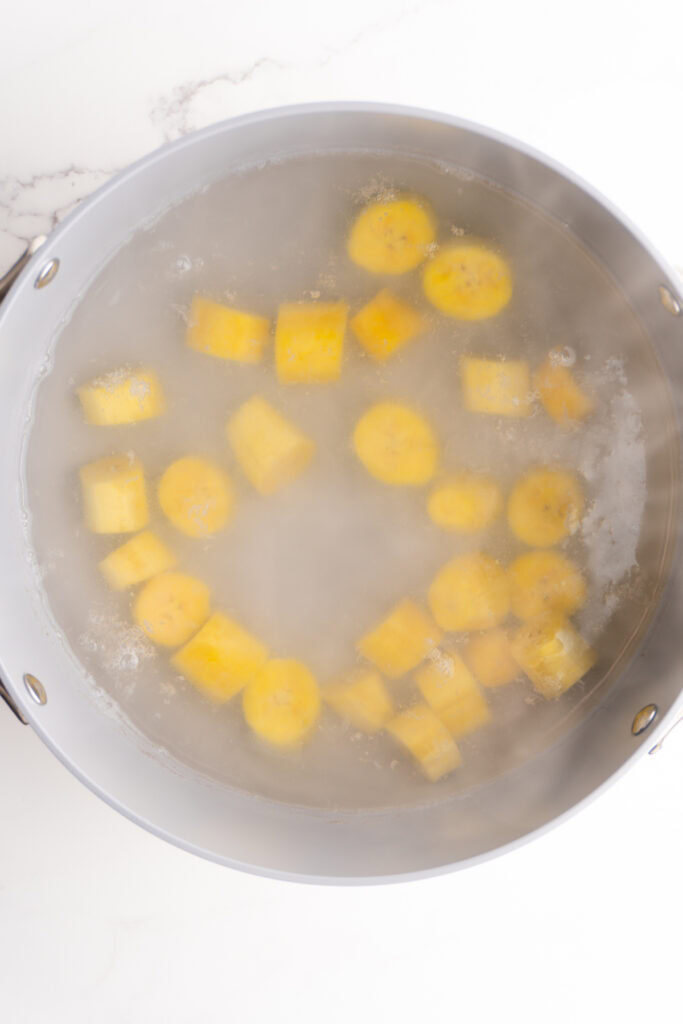 Plantain chunks boiling in a pot of water.