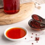 Achiote oil in a small ramekin next to whole annatto seeds.