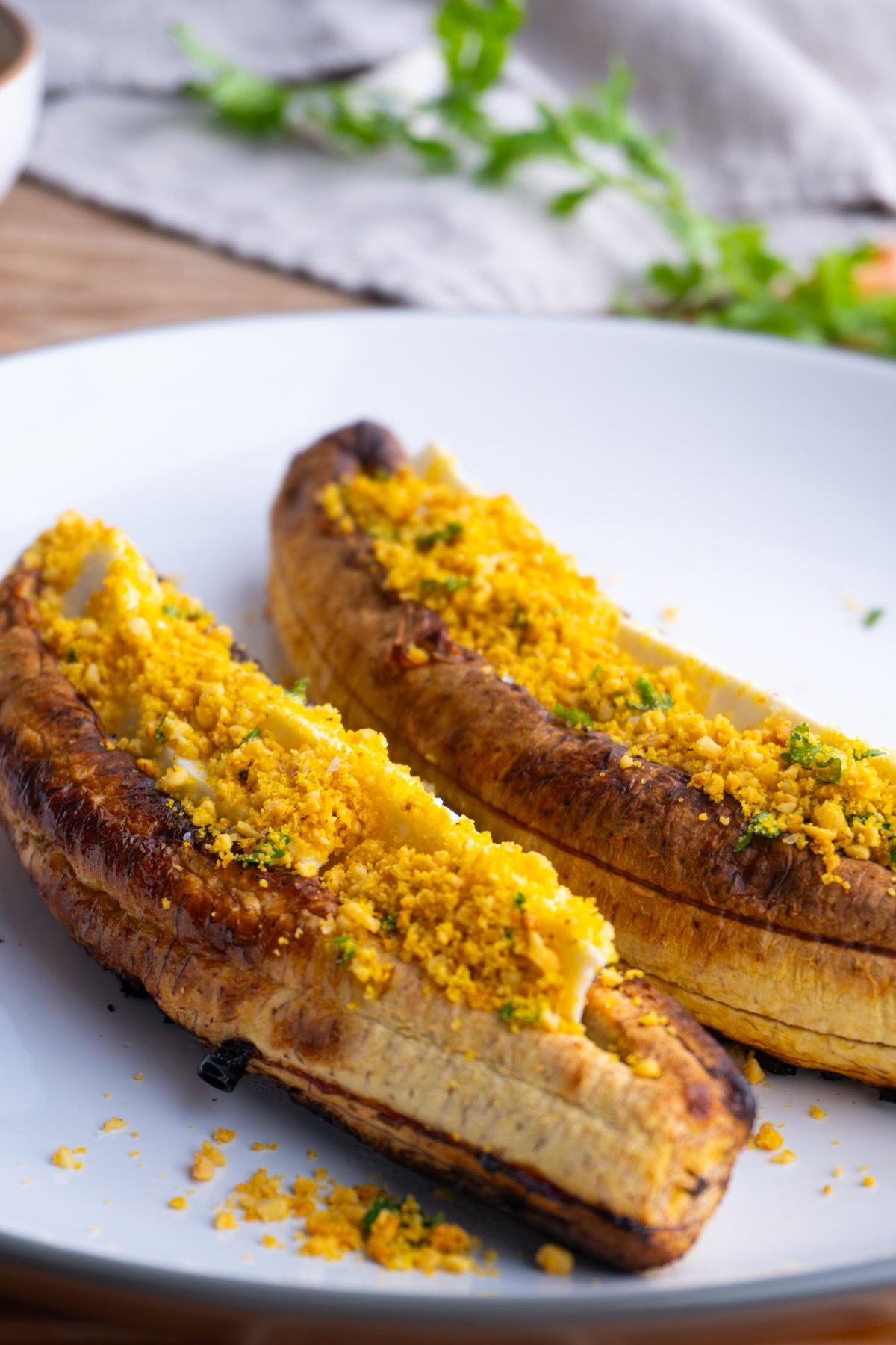 Two baked plantains with cheese and salprieta on a plate.