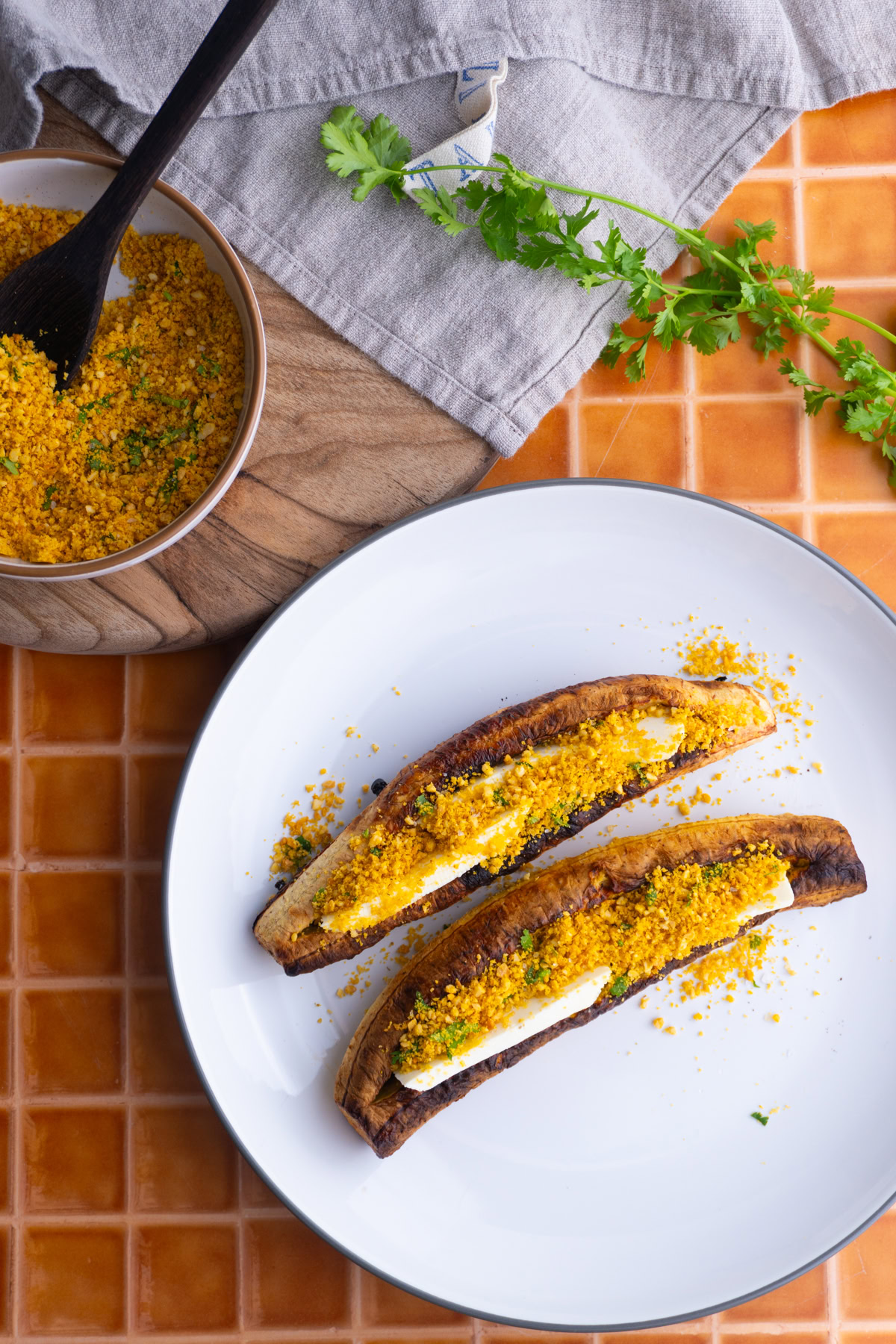 Overhead shot of two baked plantains with cheese and salprieta served with more salprieta on the side.