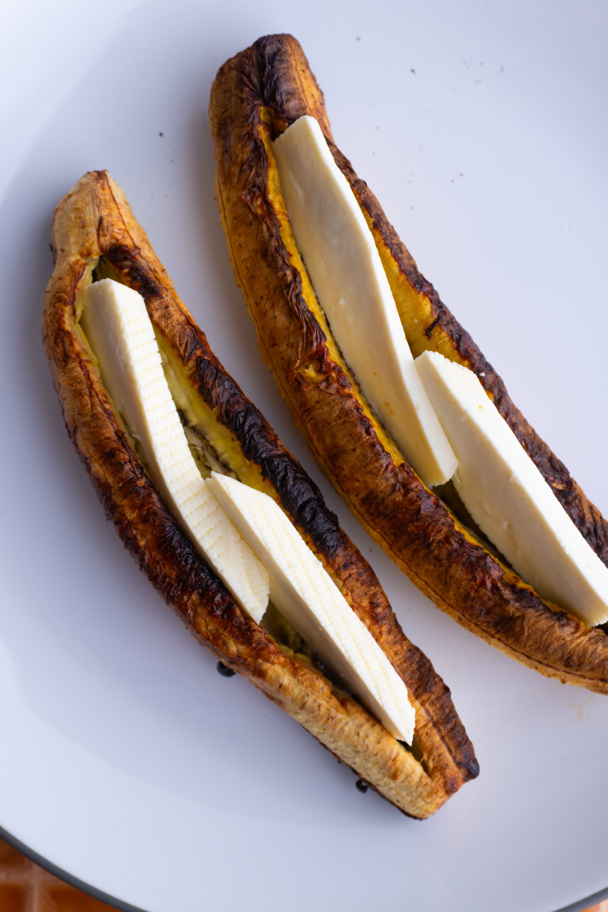 Two baked plantains stuffed with queso fresco on a plate.