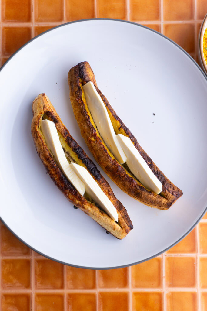 Baked plantains with cheese on a plate.
