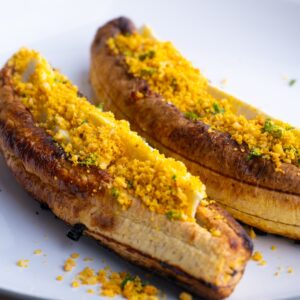 Close up of two baked sweet plantains with cheese and salprieta.