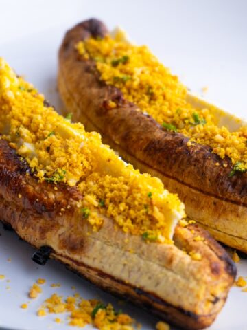 Close up of two baked sweet plantains with cheese and salprieta.