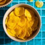 Overhead shot of green plantain chips in a bowl.