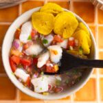 Overhead shot of Ecuadorian fish ceviche in a bowl with chifles and a spoon.