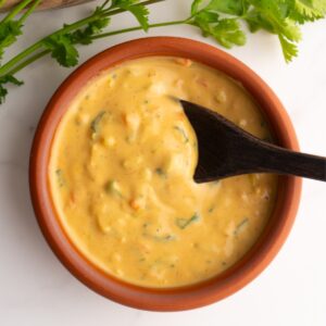 Small clay bowl with Ecuadorian peanut sauce with a wooden spoon.