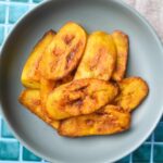Overhead shot of fried sweet plantains in a blue bowl.